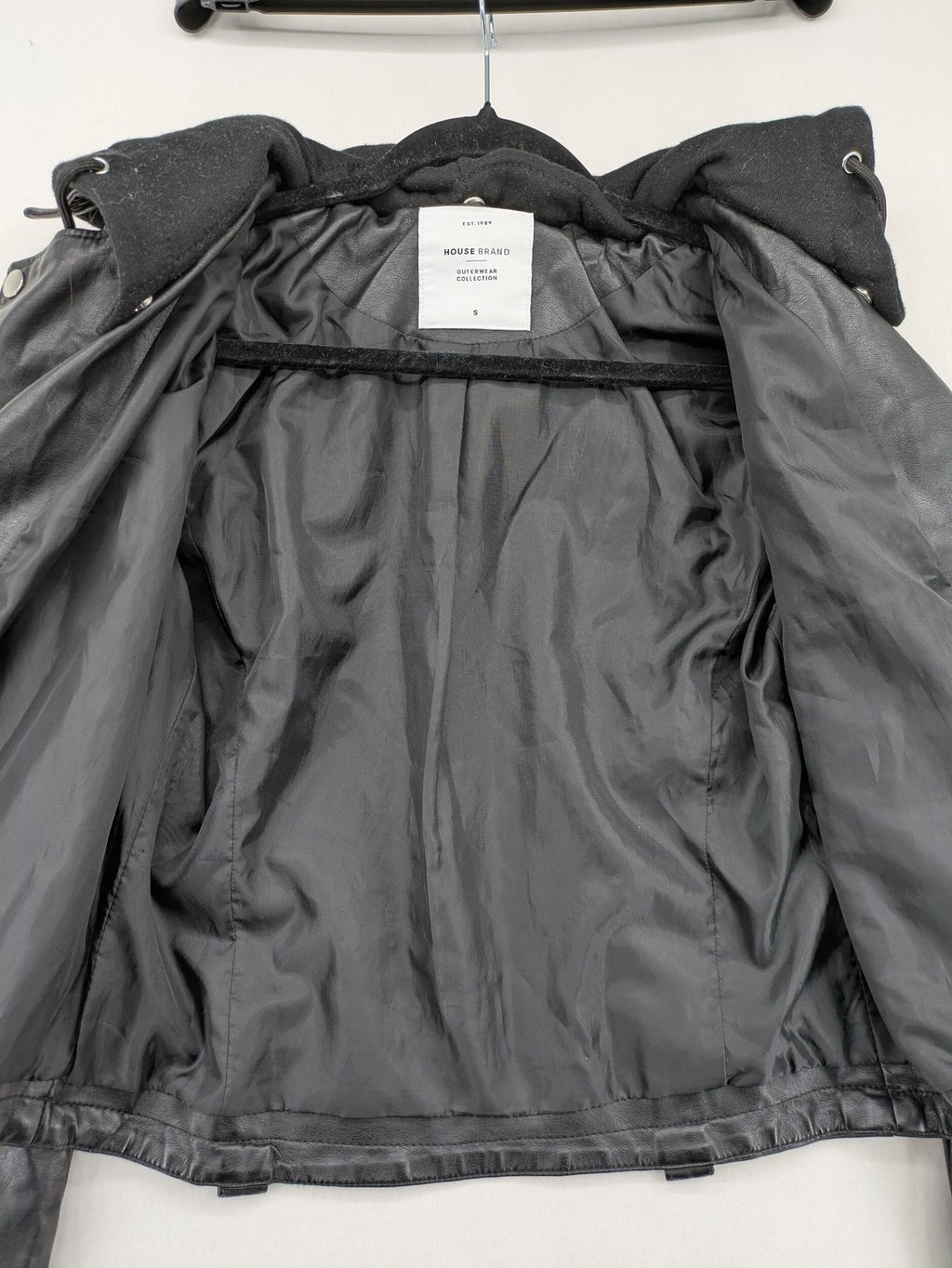 House Brand black biker jacket with hood, asymmetrical zipper, and belt detail.