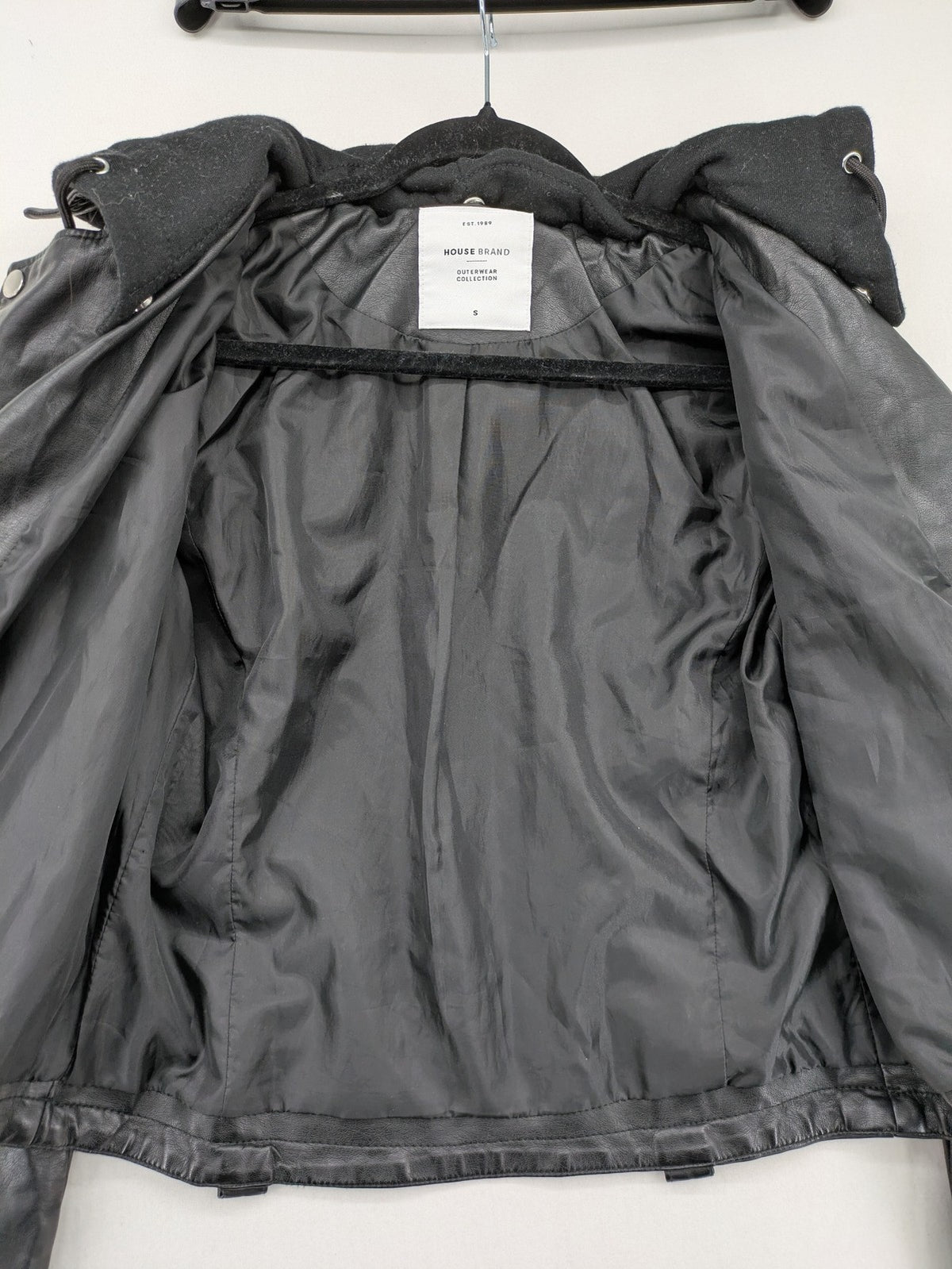 House Brand black biker jacket with hood, asymmetrical zipper, and belt detail.