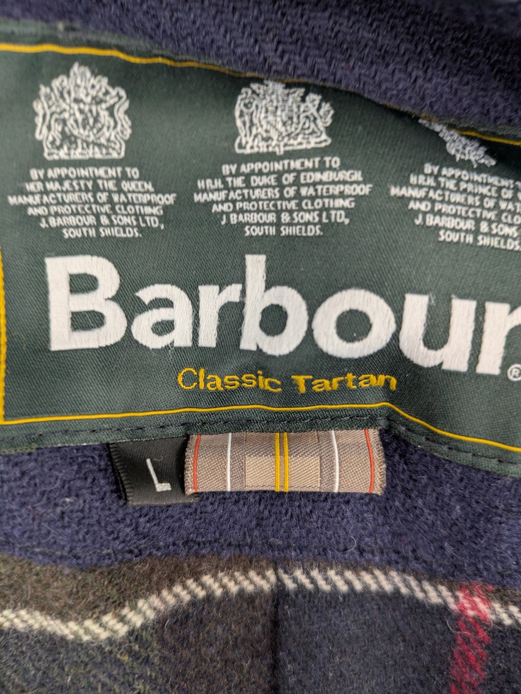 Barbour navy wax jacket with quilted lining and leather elbow patches, tartan interior.