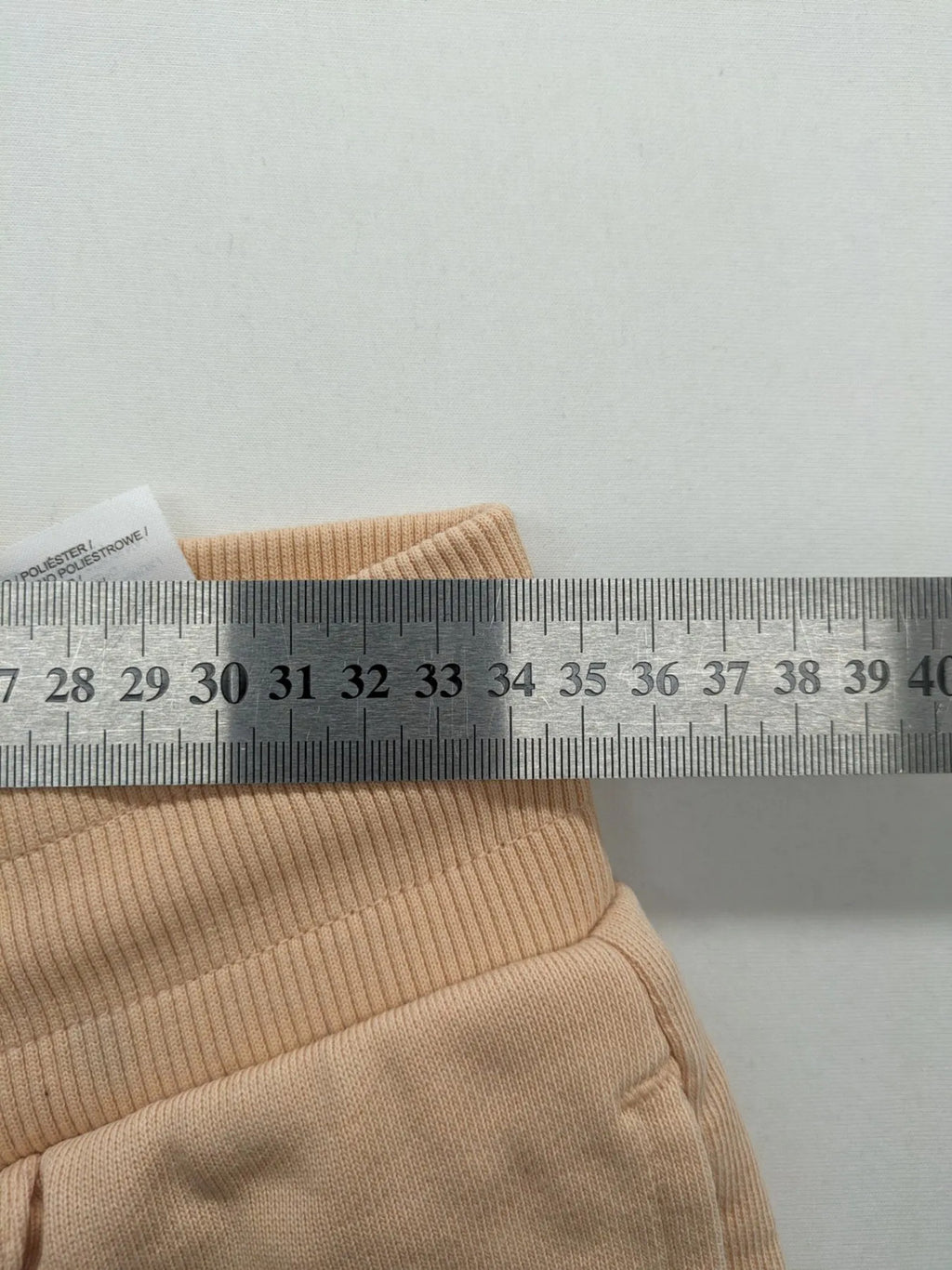Hummel beige jogging pants with adjustable drawstring, embroidered logo, and ankle cuffs.