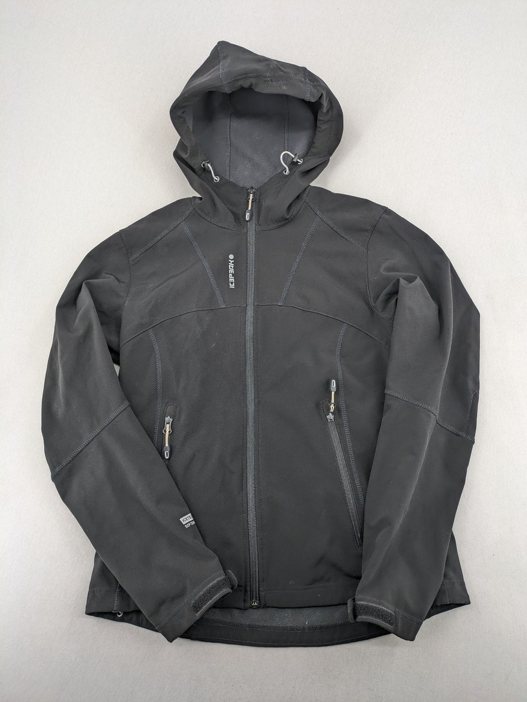 Icepeak black softshell jacket with fleece lining, adjustable hood, and zippered pockets.
