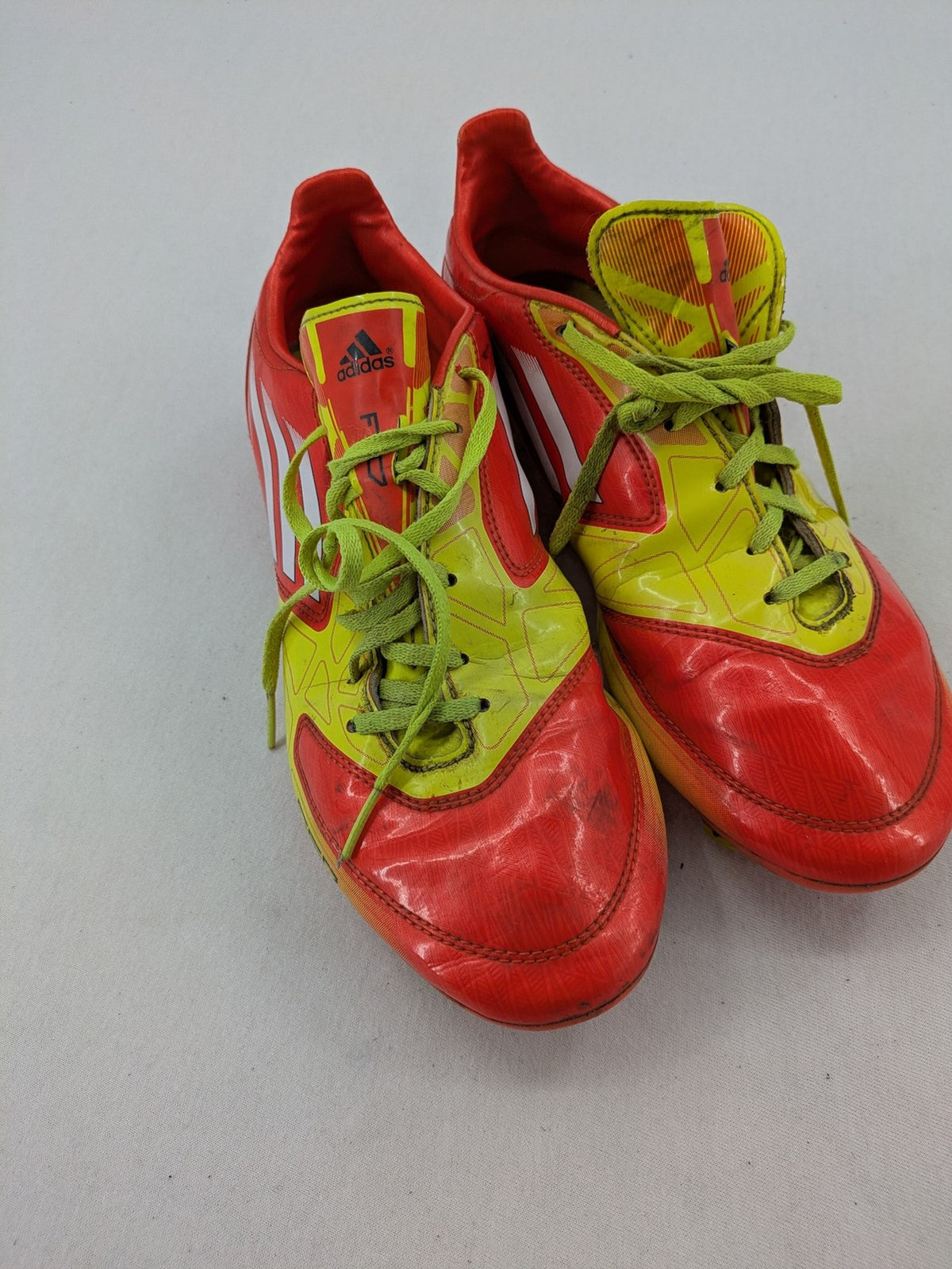 Adidas F50 soccer shoes red and yellow with three-stripe logo and lightweight synthetic material.