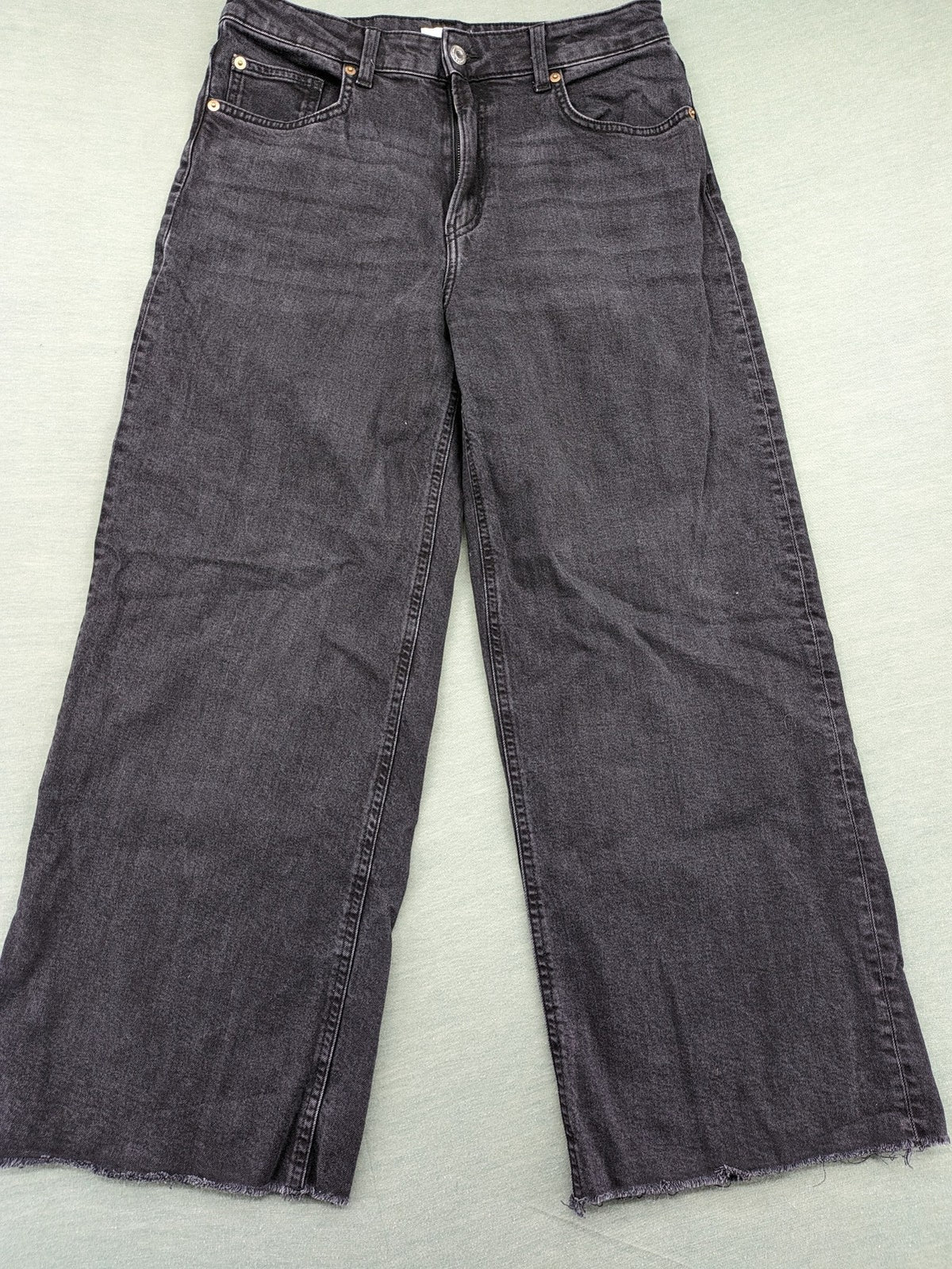 H&M black grey wide leg cropped jeans with frayed hem and high waist design.