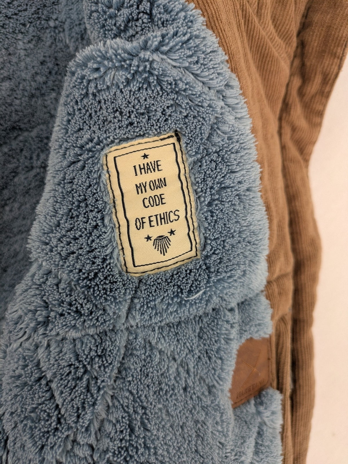 Naketano blue jacket with teddy fleece lining, hood, and leather appliqués.
