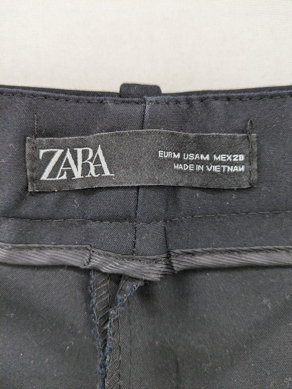 Zara black pants with front creases, subtle slit hem, and buttoned back pocket.