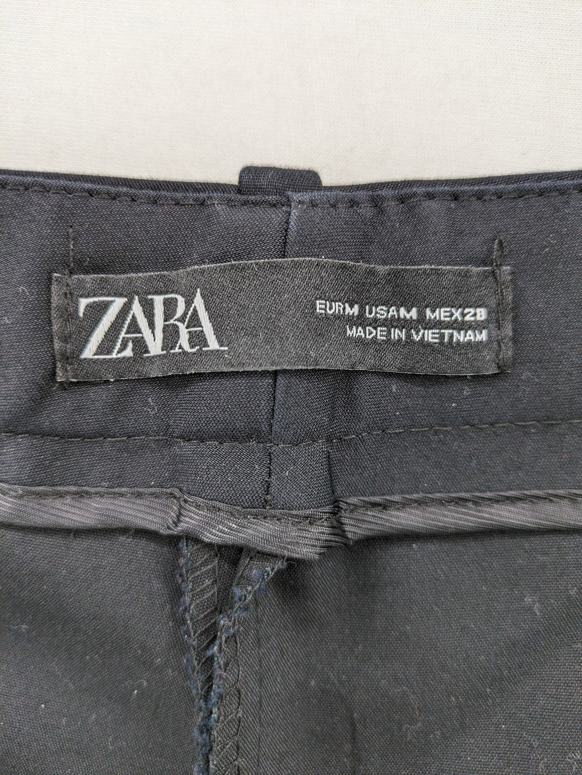 Zara black pants with front creases, subtle slit hem, and buttoned back pocket.