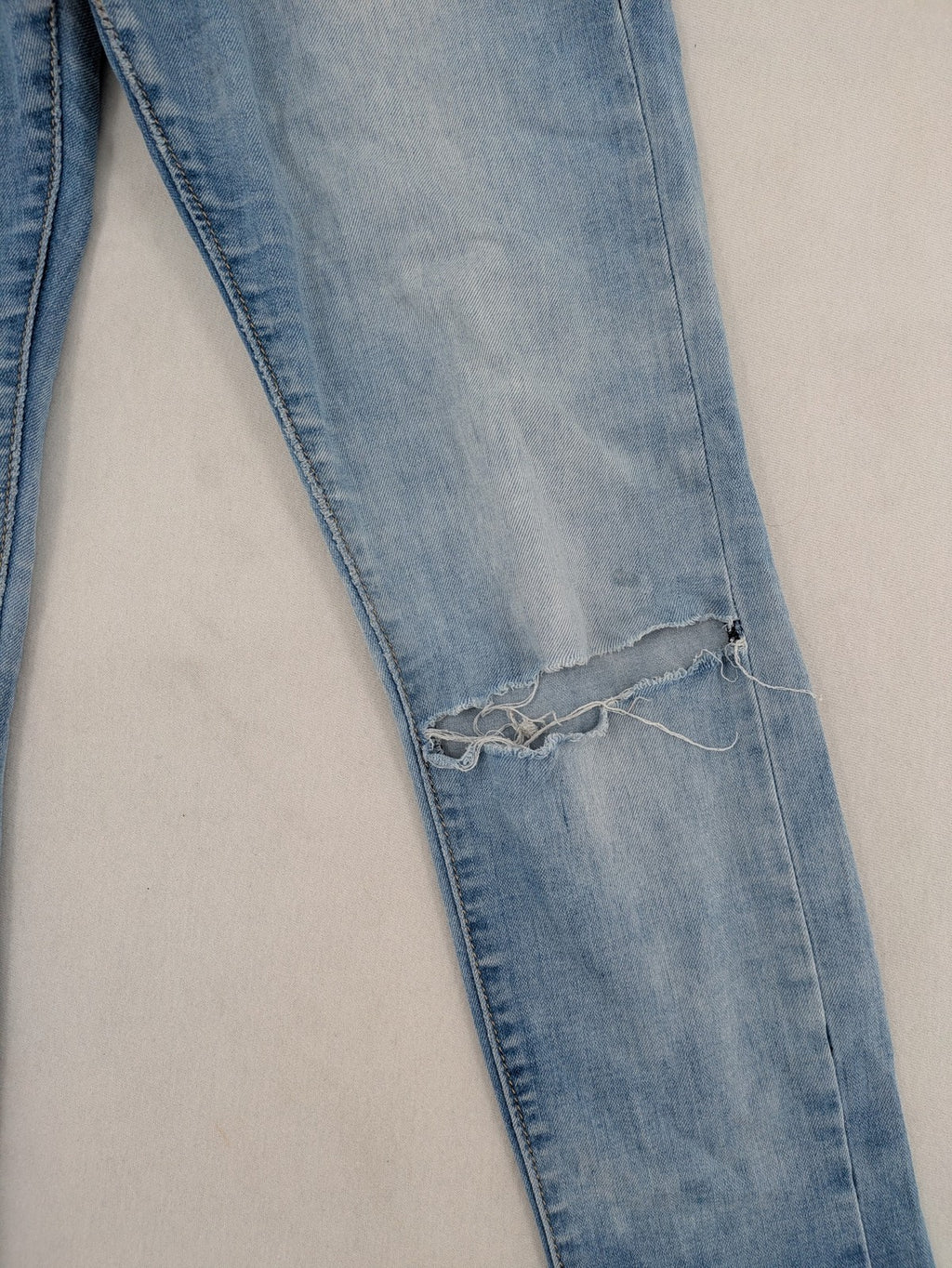 Lexxury blue skinny jeans distressed with knee rips and light wash finish.