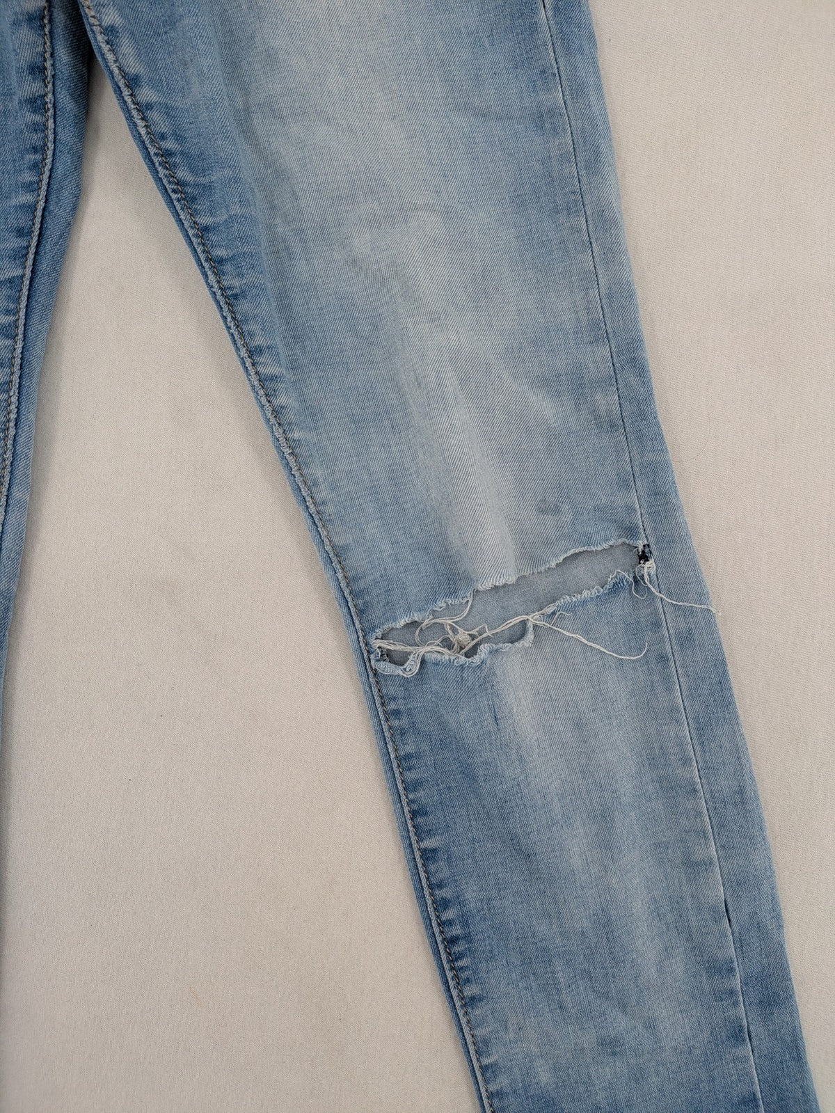 Lexxury blue skinny jeans distressed with knee rips and light wash finish.