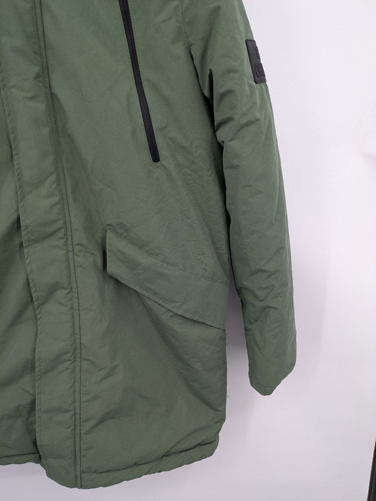 Bad Choices green parka coat with reflective details and logo patch on sleeve.