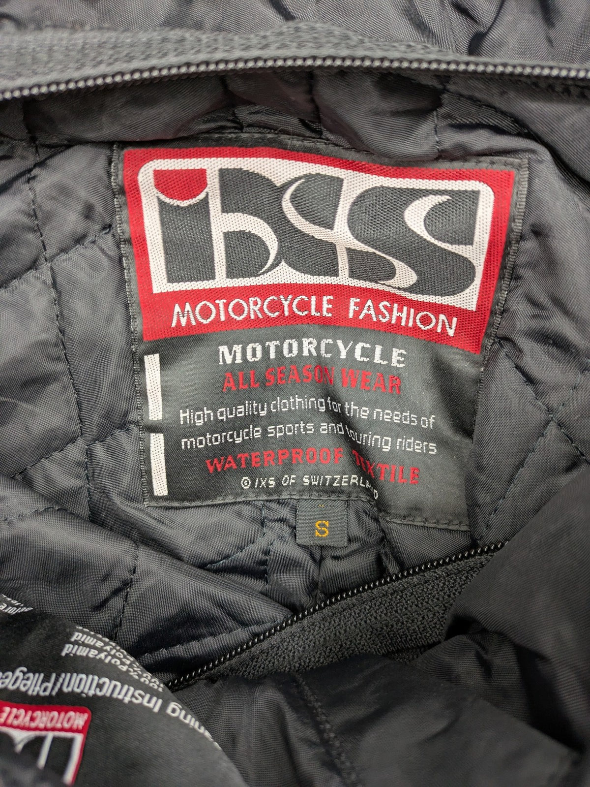 iXS black chaps with grey accents, waterproof textile, adjustable belt, reinforced knees.