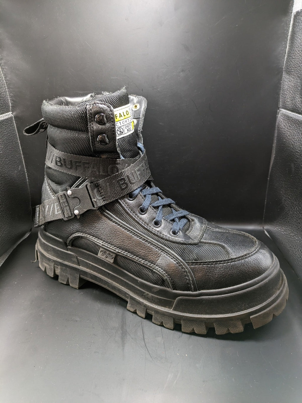 Buffalo black motorcycle boots with chunky sole, adjustable buckle strap, and red plaid lining.