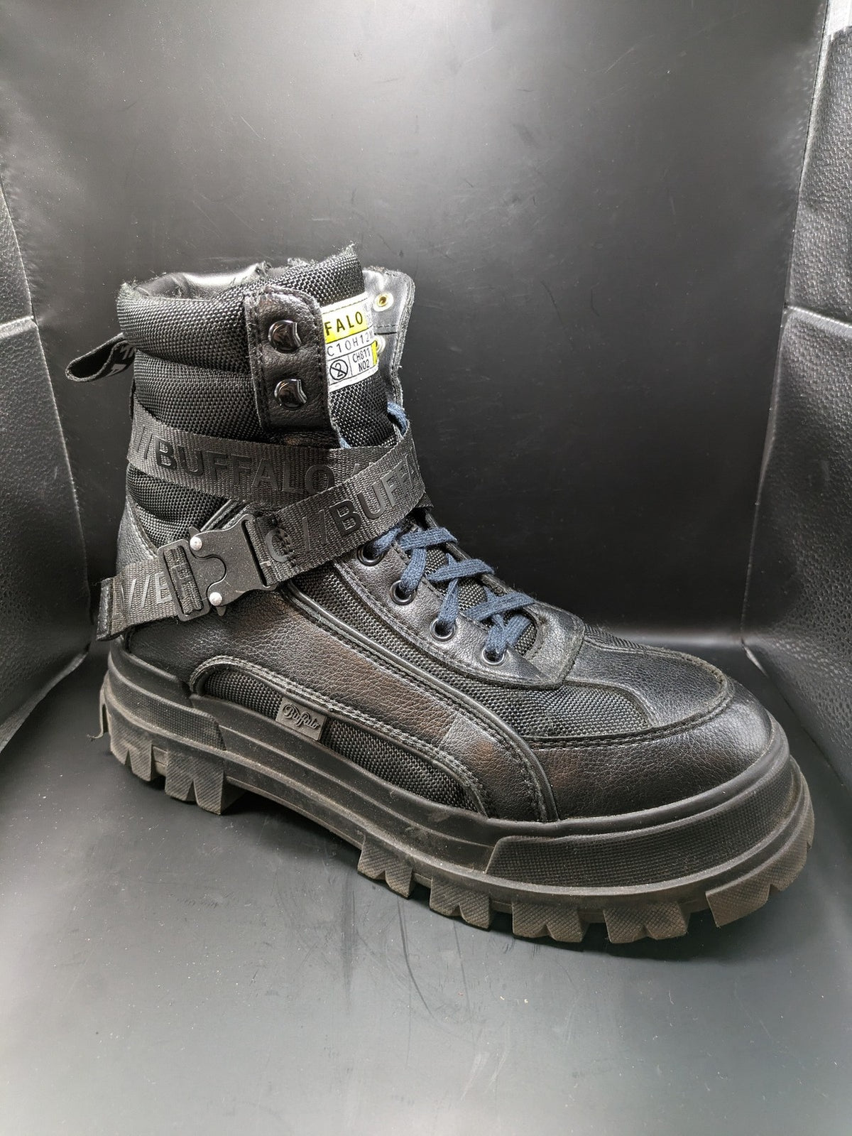 Buffalo black motorcycle boots with chunky sole, adjustable buckle strap, and red plaid lining.