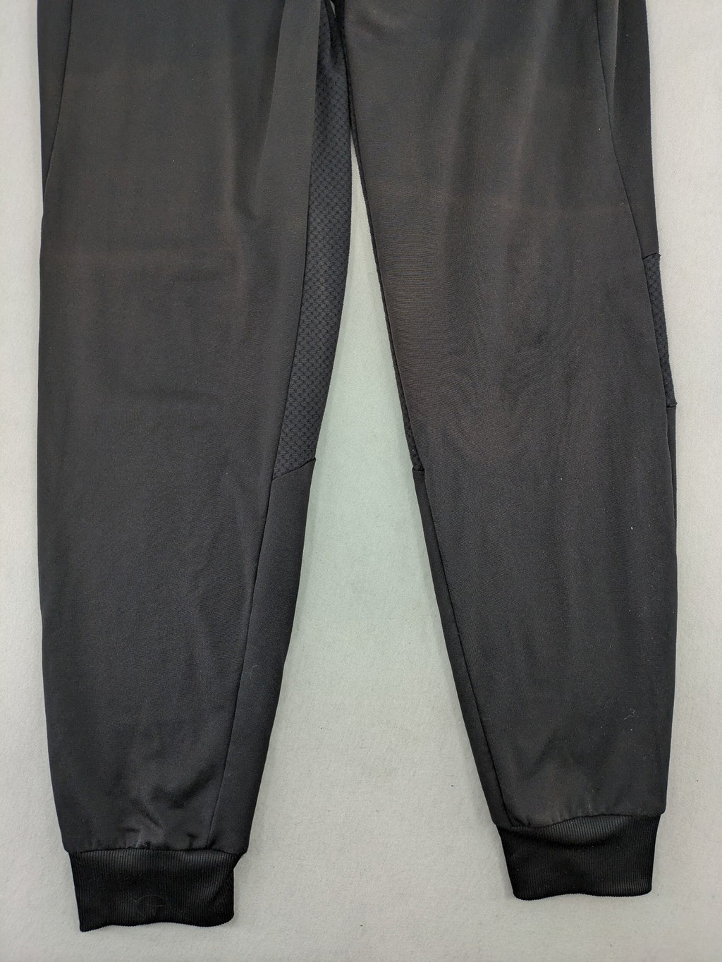 Kalenji black loungewear pants with grey accents and zippered side pockets.