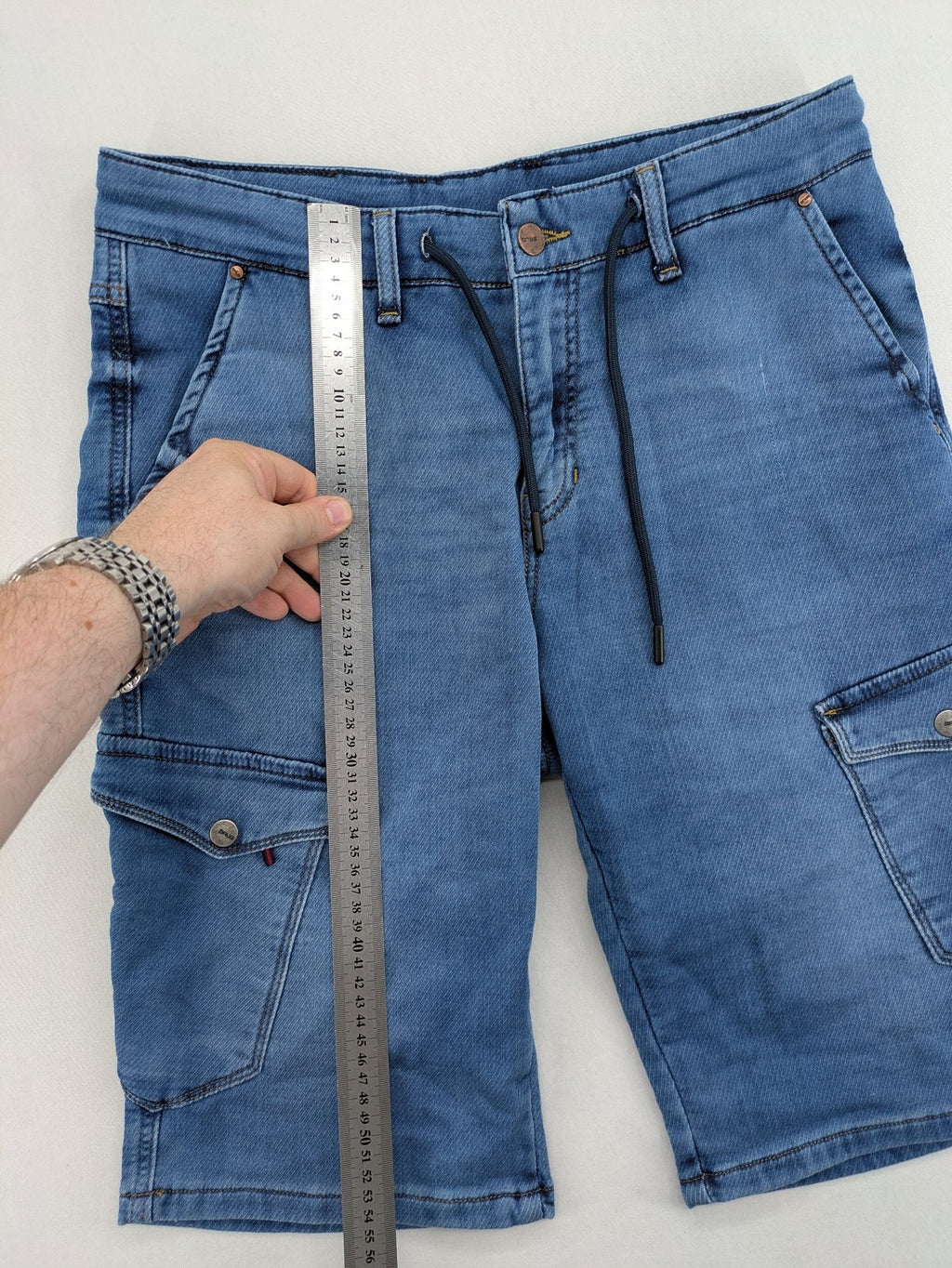Herren blue denim cargo shorts with adjustable drawstring and multiple buttoned side pockets.