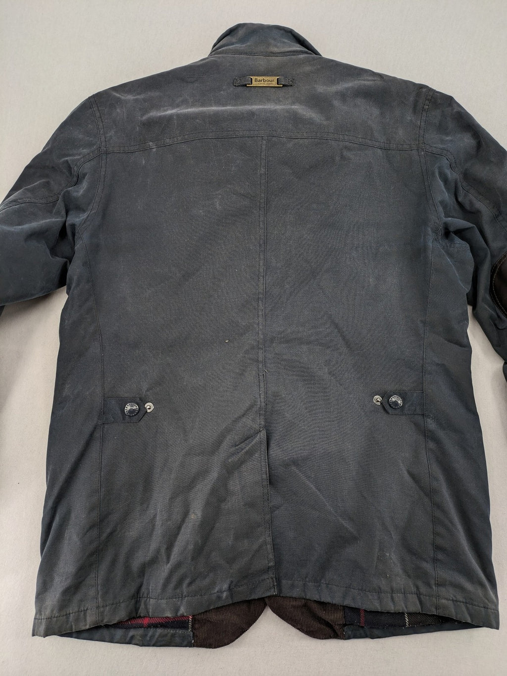 Barbour navy wax jacket with quilted lining and leather elbow patches, tartan interior.