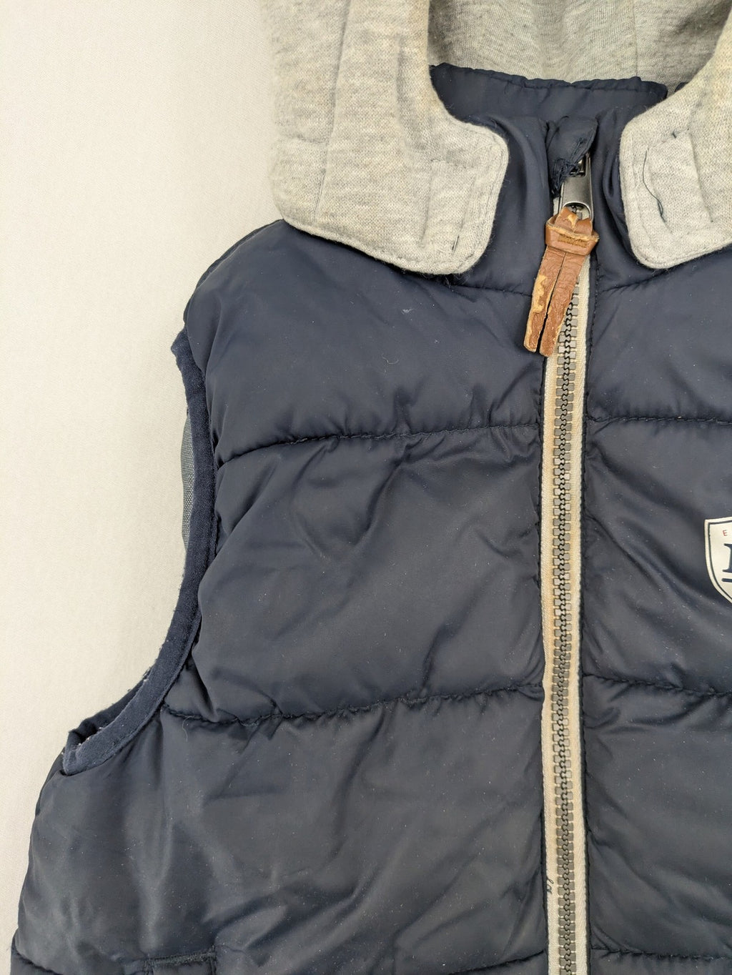 H&M navy puffer vest with grey hood and zip pockets for kids.