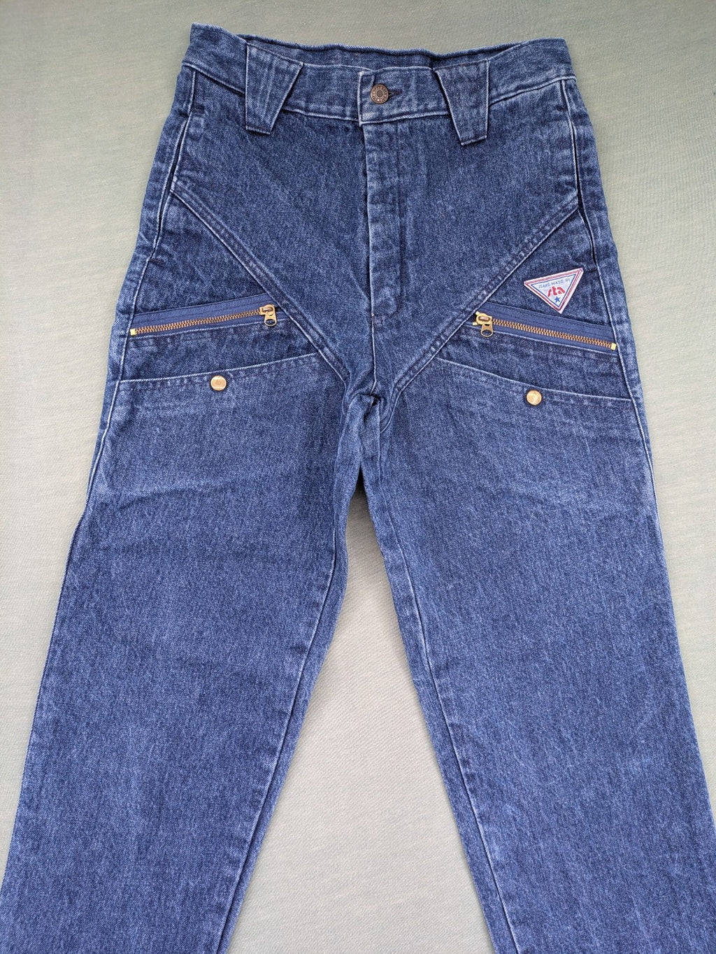 YKK blue high waist mom jeans with decorative front zipper pockets and vintage denim texture.