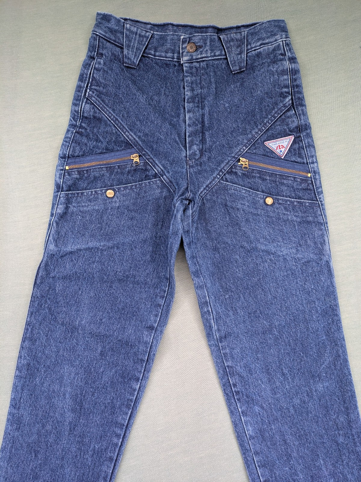 YKK blue high waist mom jeans with decorative front zipper pockets and vintage denim texture.