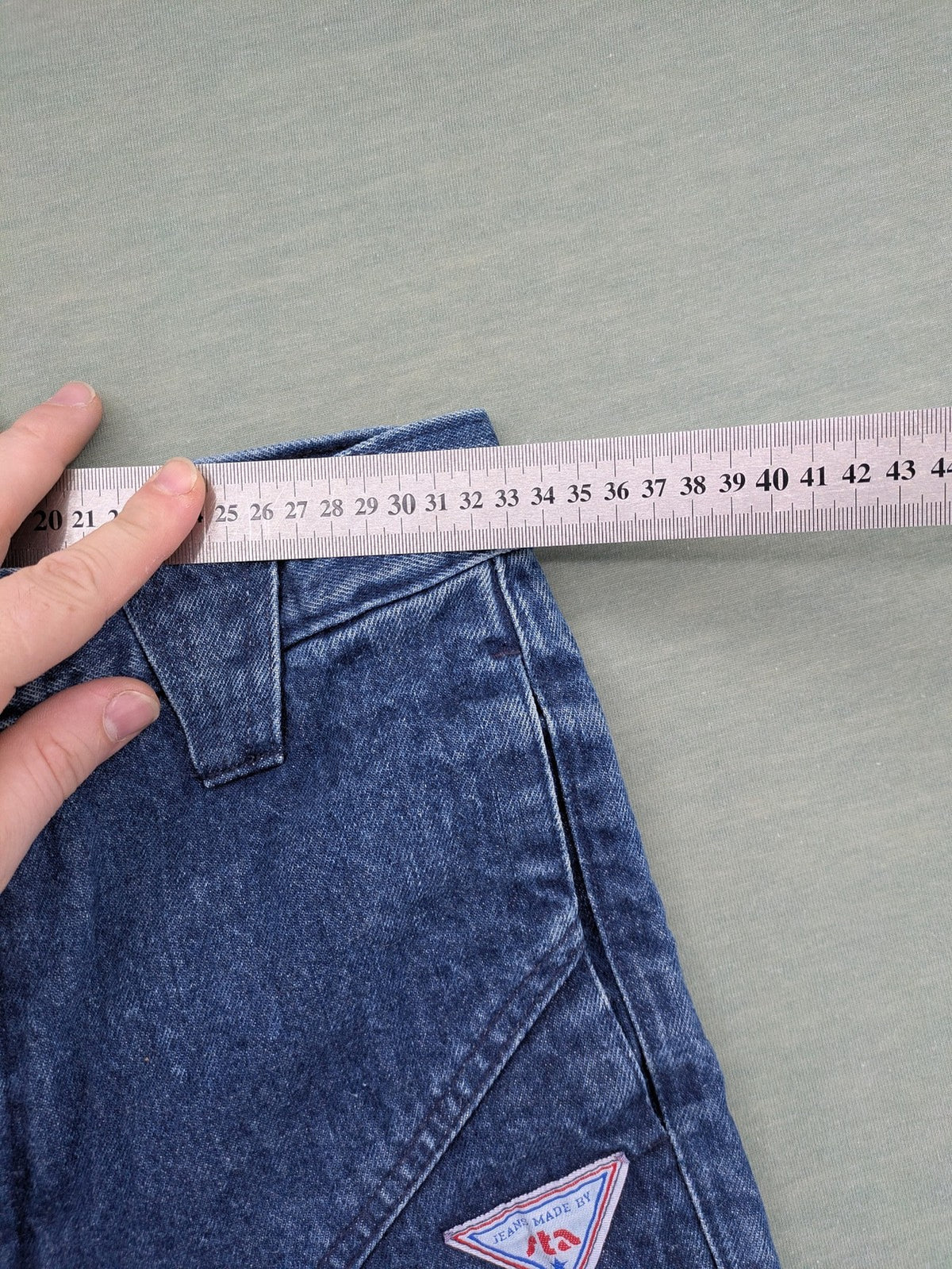 YKK blue high waist mom jeans with decorative front zipper pockets and vintage denim texture.