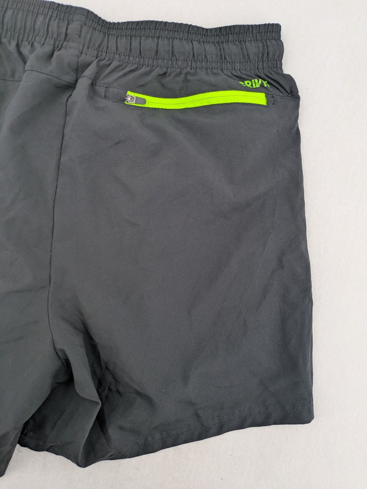 Crivit black running shorts with neon green accents, elastic waistband, and reflective details.