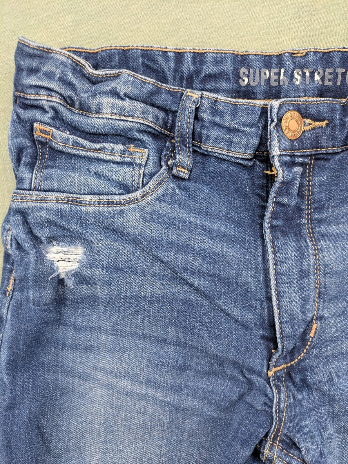 H&M blue skinny jeans with distressed knee details and classic 5-pocket design.