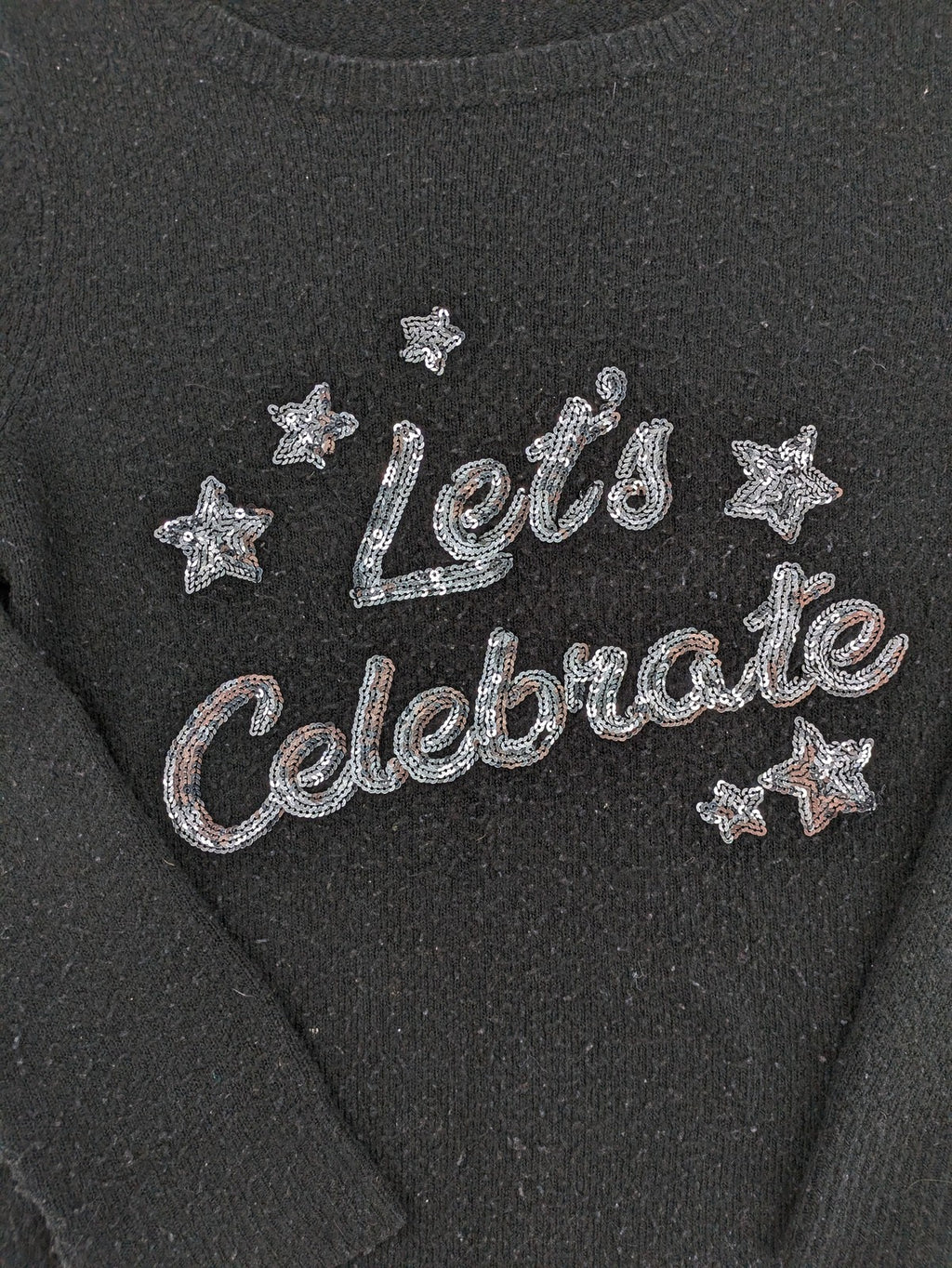 Yessica black turtle neck jumper with sequin "Let's Celebrate" graphic and star details.