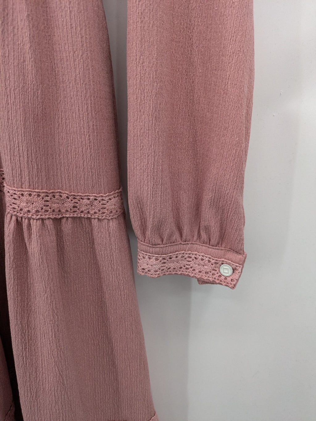Moda pink bridal party dress with lace inserts, long sleeves, and tiered design.