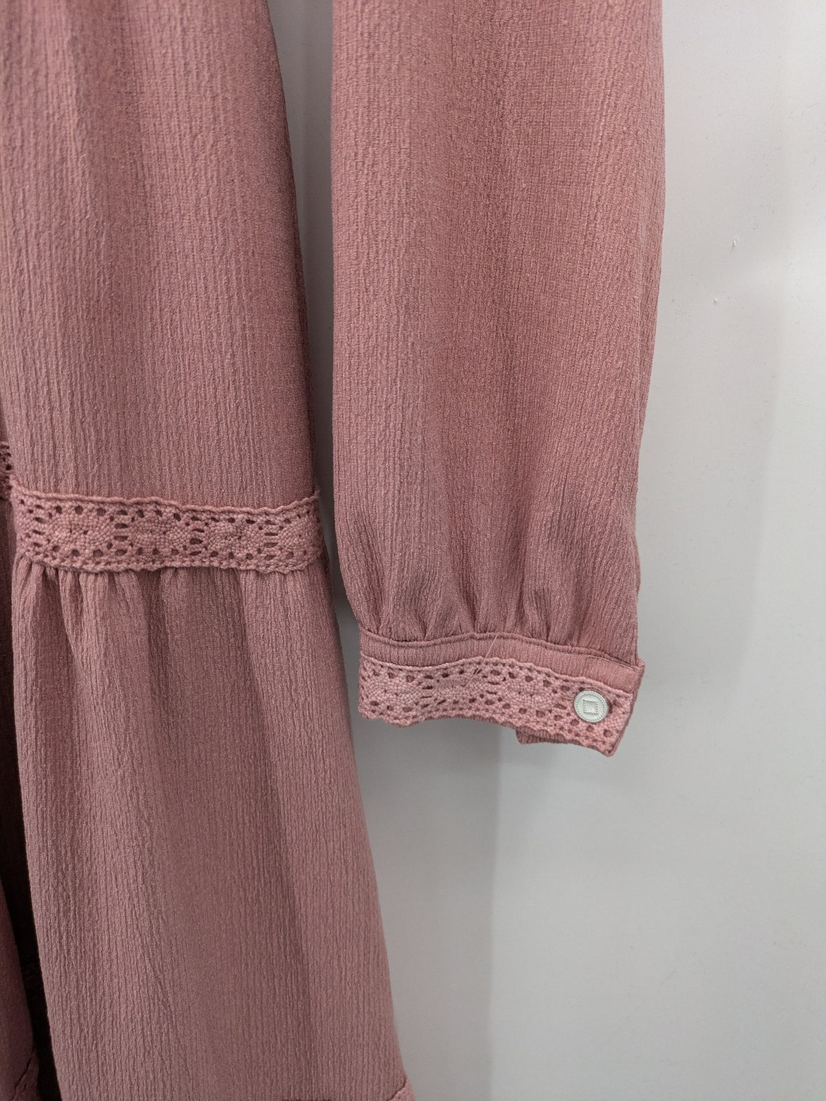Moda pink bridal party dress with lace inserts, long sleeves, and tiered design.