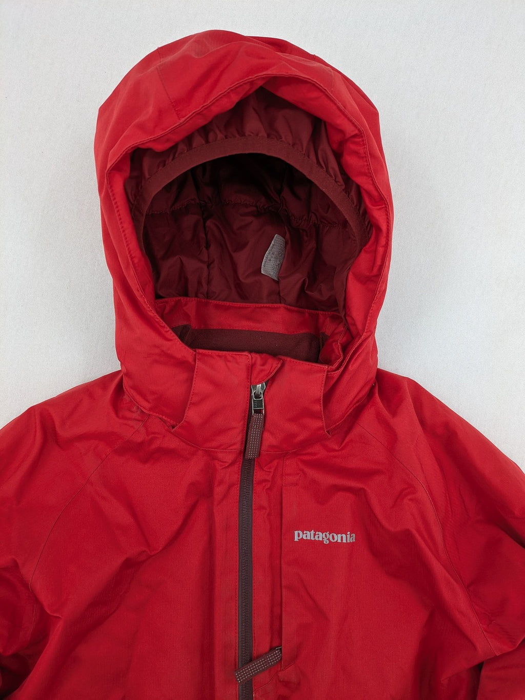 Patagonia red winter coat with hood, zip closure, snow skirt, and ski pass pocket.