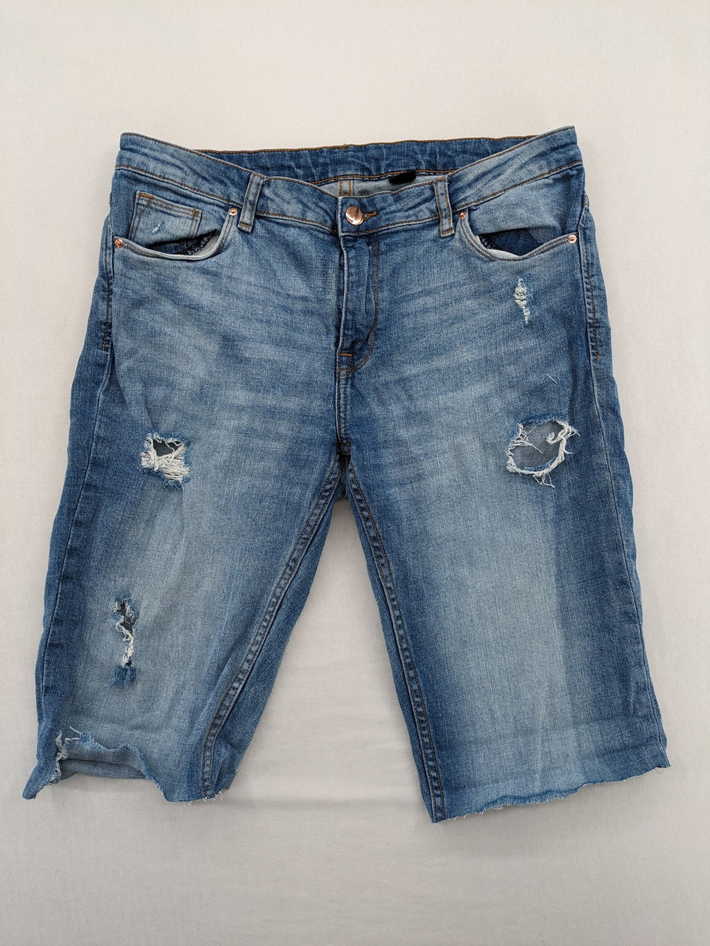 Denim blue distressed jeans shorts with frayed edges and a trendy used look.