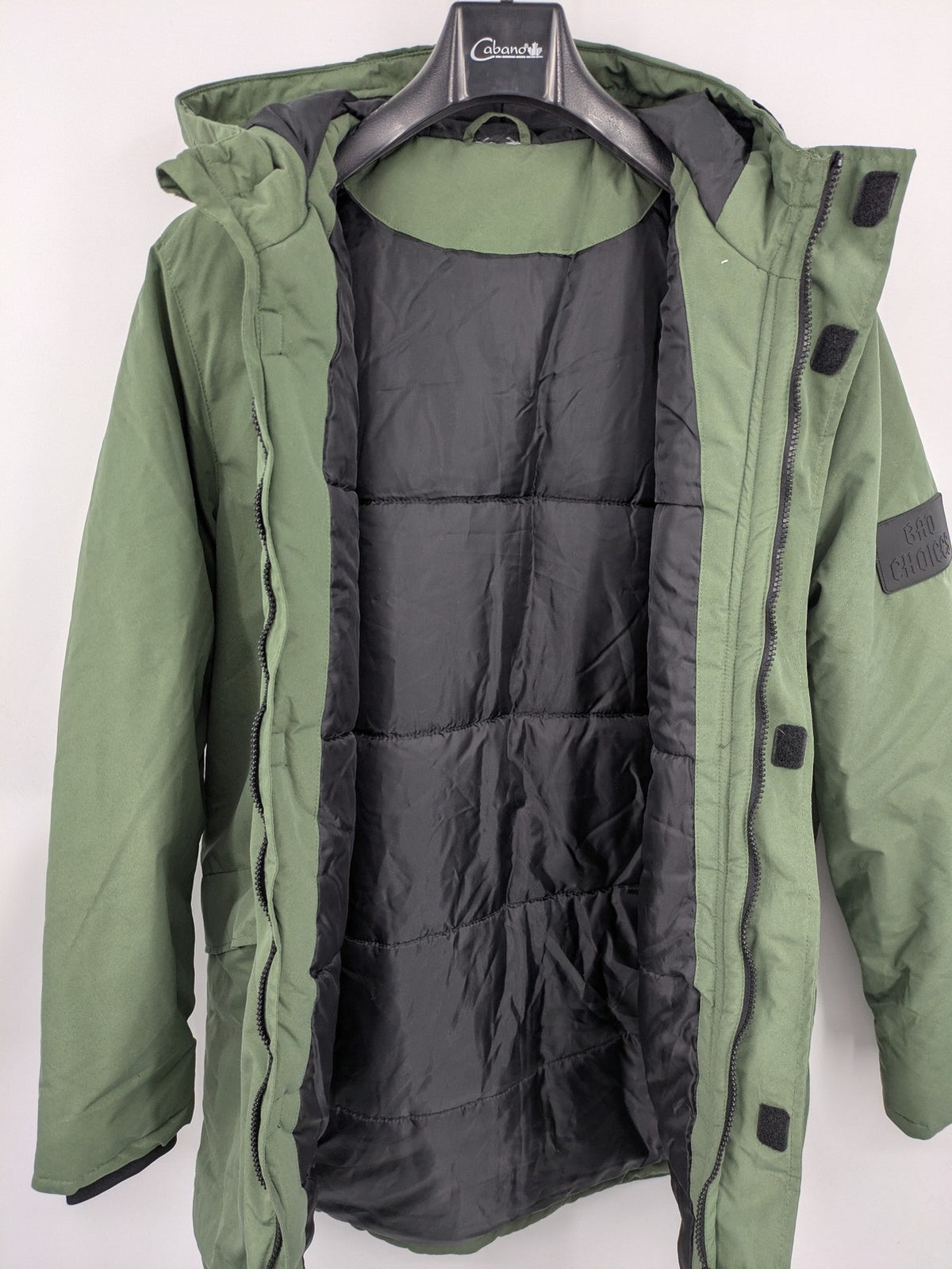 Bad Choices green parka coat with reflective details and logo patch on sleeve.