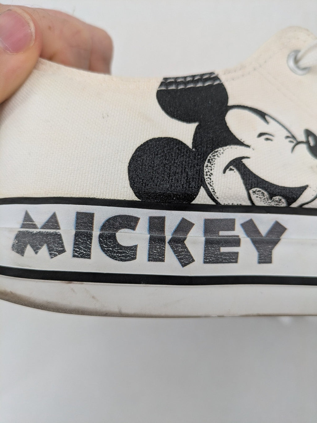 Disney Mickey Mouse white canvas low top sneakers with iconic Mickey Mouse graphic.