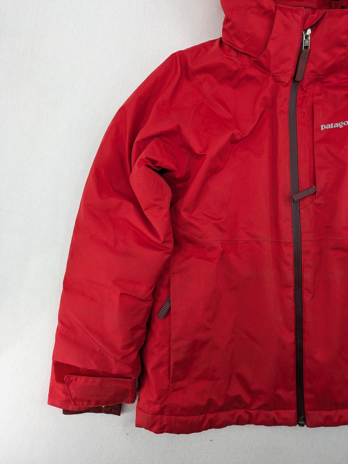 Patagonia red winter coat with hood, zip closure, snow skirt, and ski pass pocket.