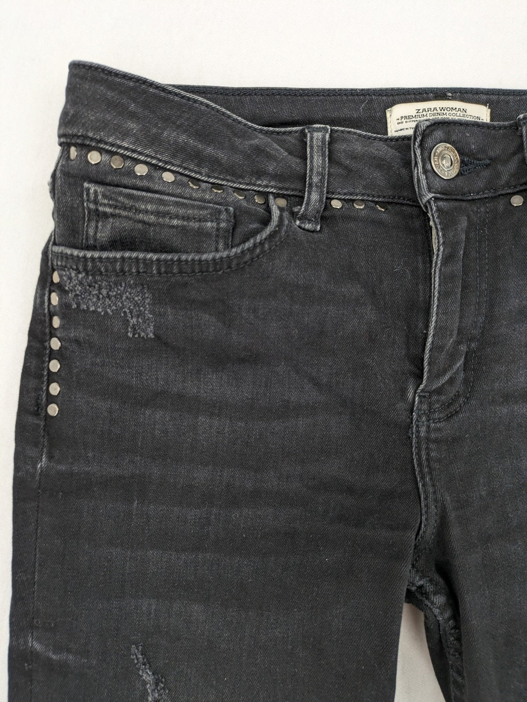 Zara Woman black skinny jeans with distressed details, silver studs, and frayed hem.