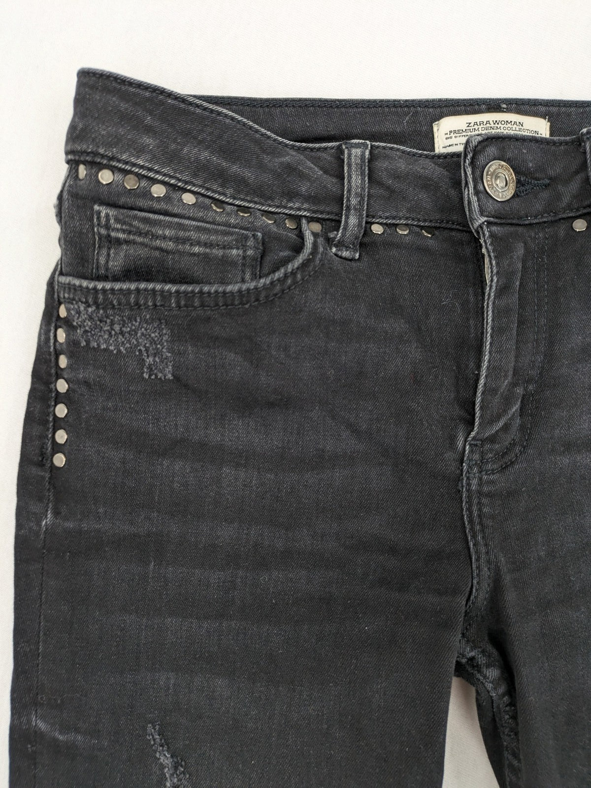 Zara Woman black skinny jeans with distressed details, silver studs, and frayed hem.