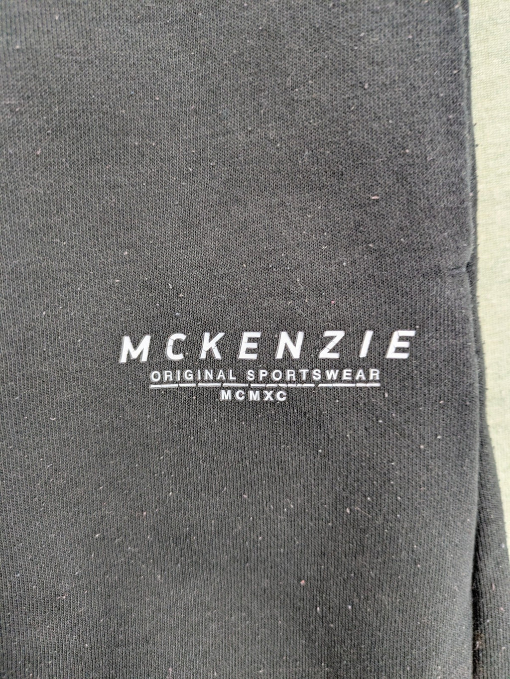 McKenzie black joggers with white logo, tapered fit, and ribbed ankle cuffs.
