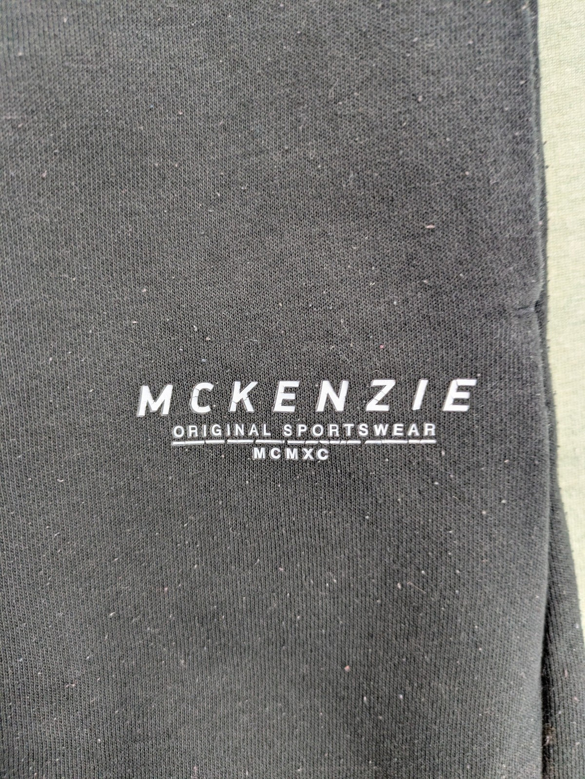 McKenzie black joggers with white logo, tapered fit, and ribbed ankle cuffs.