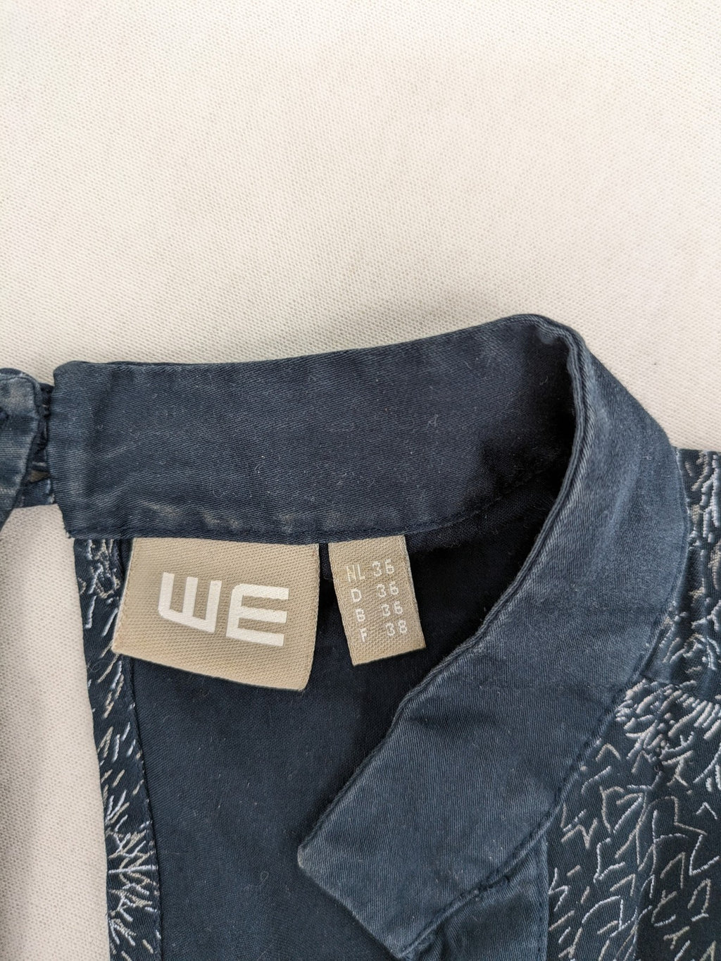 Muster navy dress with white abstract dandelion print, V-neck and collar details.
