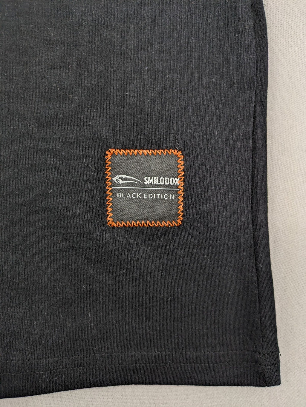 Smilodox black T-shirt minimalist design with subtle brand patch, 100% cotton.