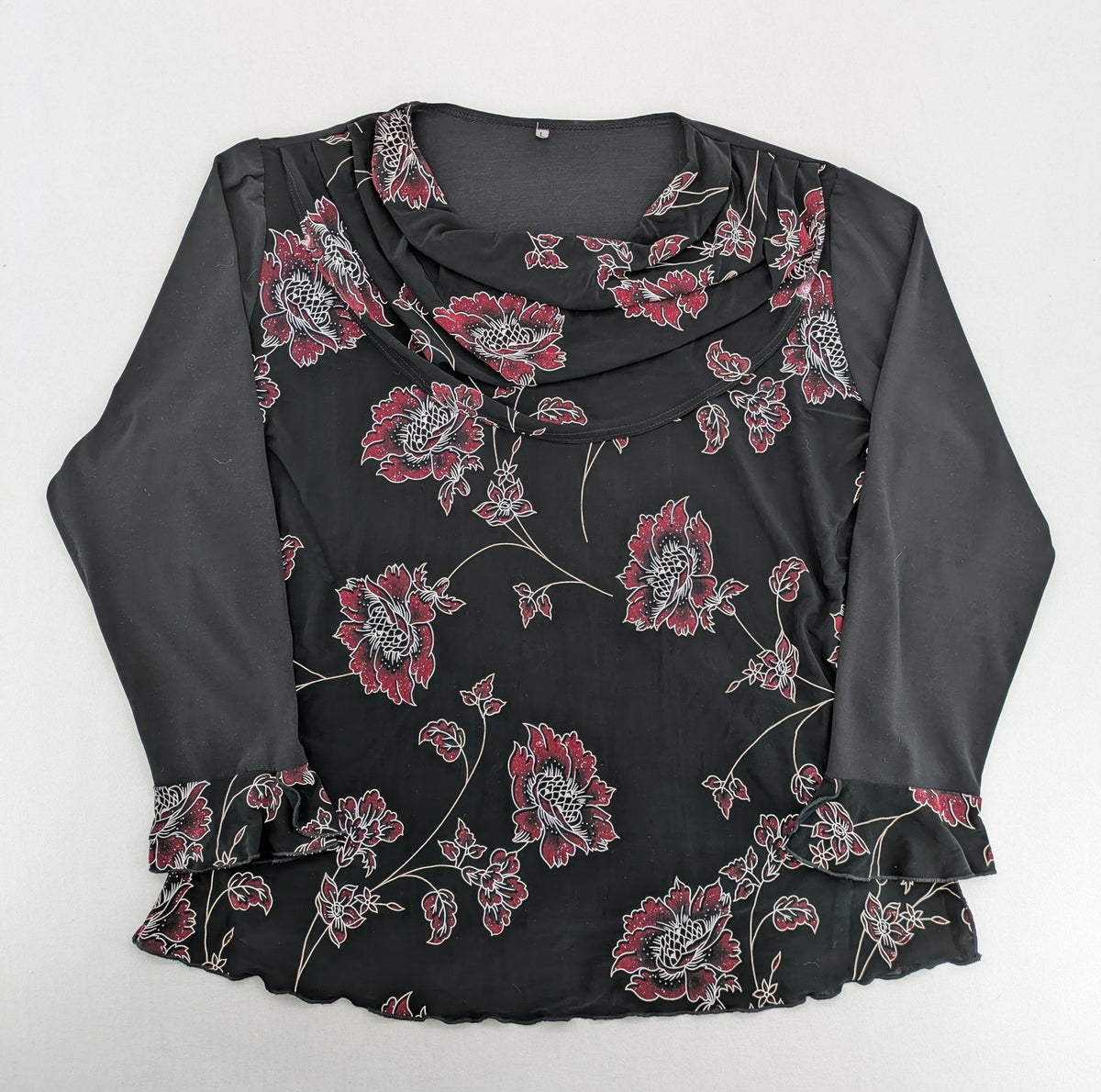 Damen black top with burgundy and white floral print, waterfall collar, and ruffled sleeves.