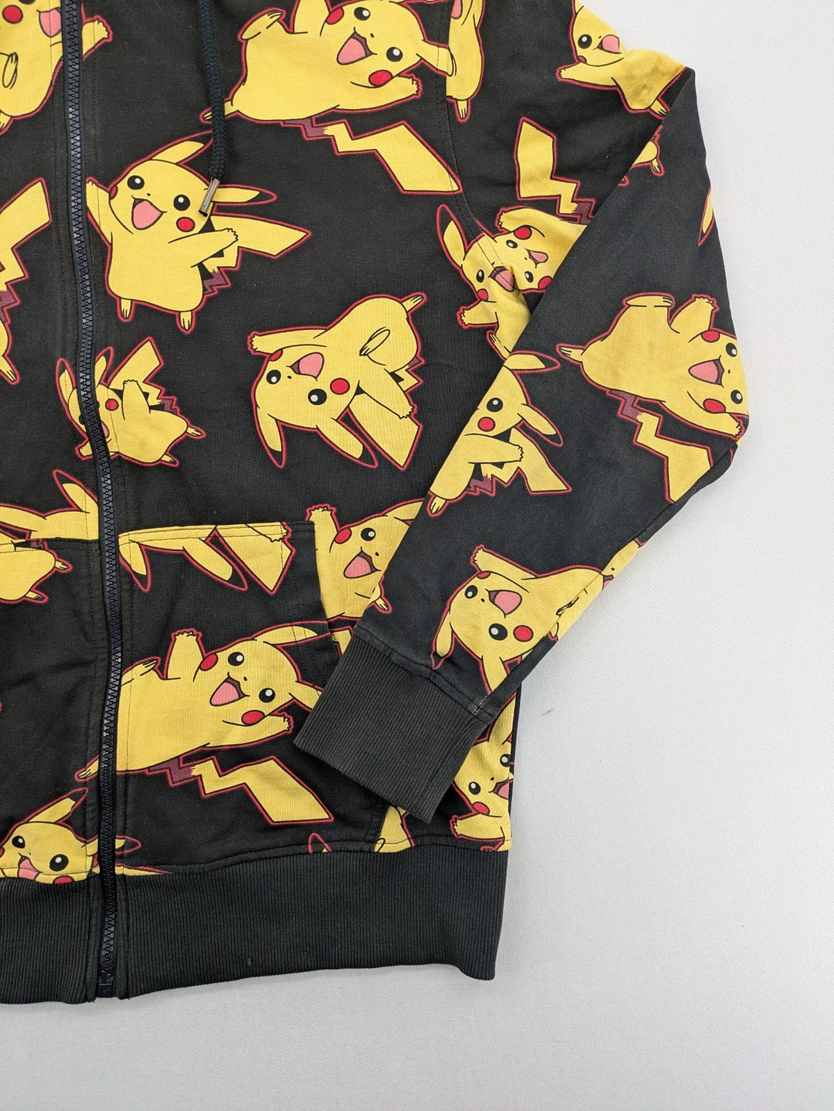 Herren black zip-through hoodie with vibrant Pikachu allover print and yellow lining.