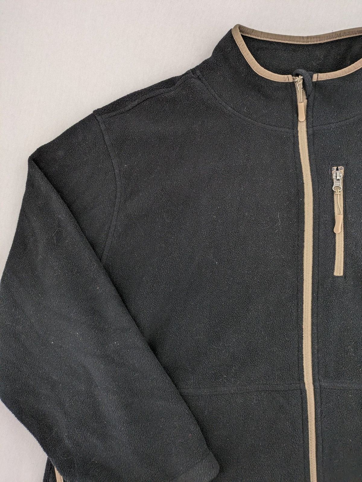 Crane beige and black fleece jacket full zip with cream accents and zippered pockets.