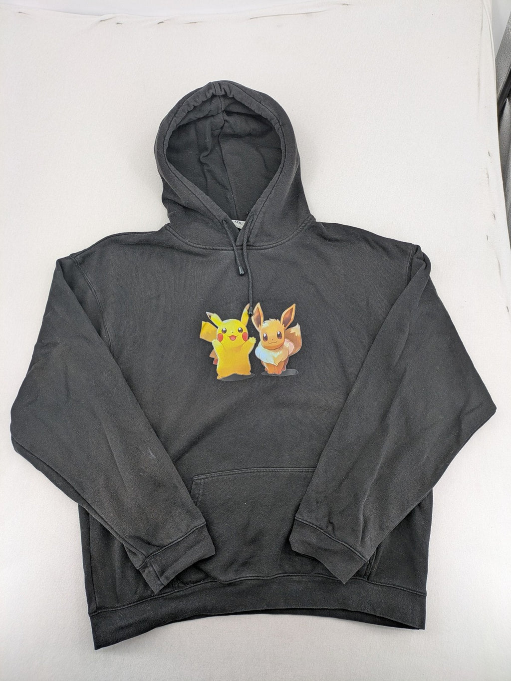 Pokémon black hoodie featuring colorful Pikachu and Evoli graphic, classic pullover style.