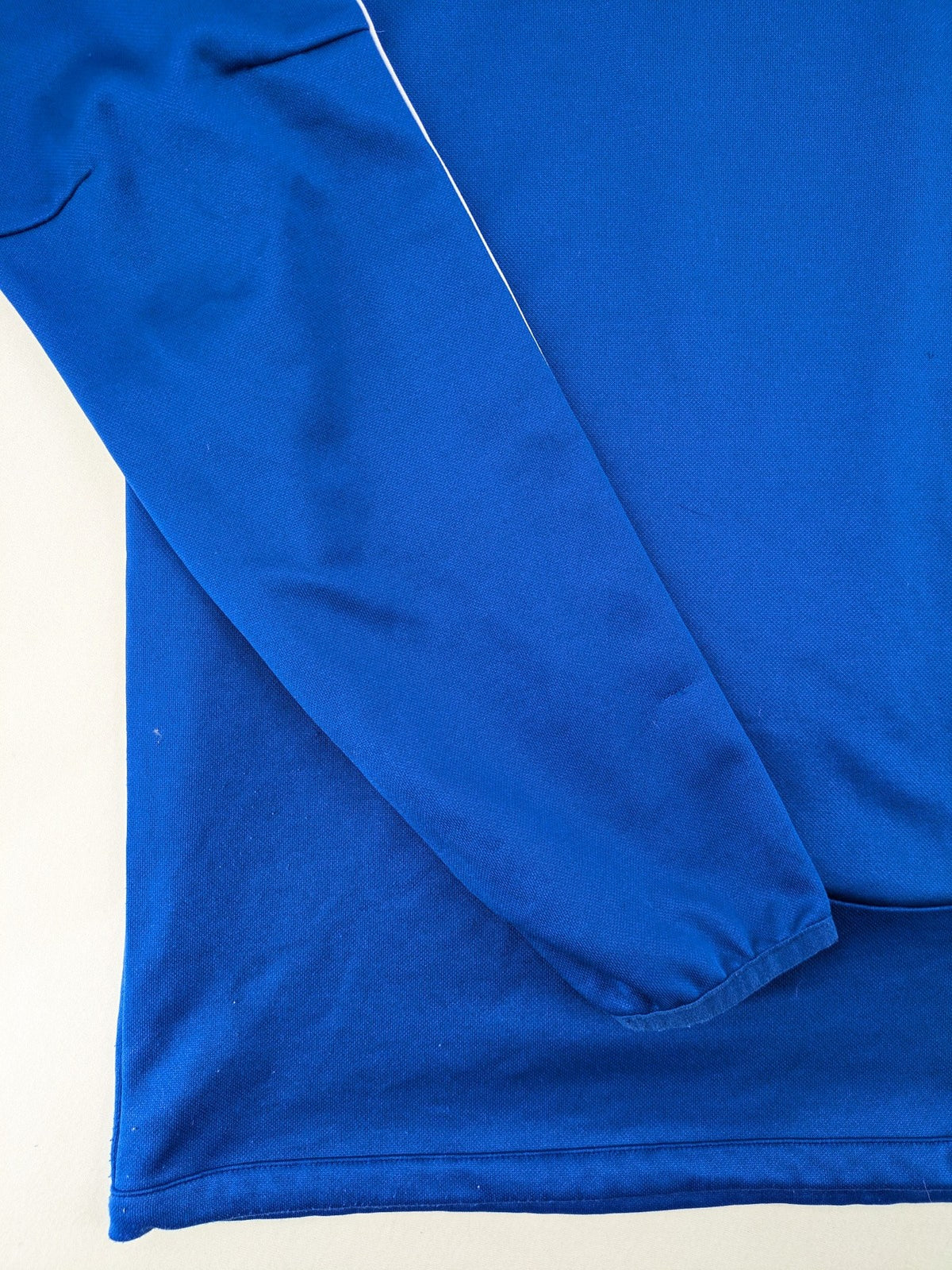 Adidas blue long sleeve top with white three stripes and 1/4 zip collar.