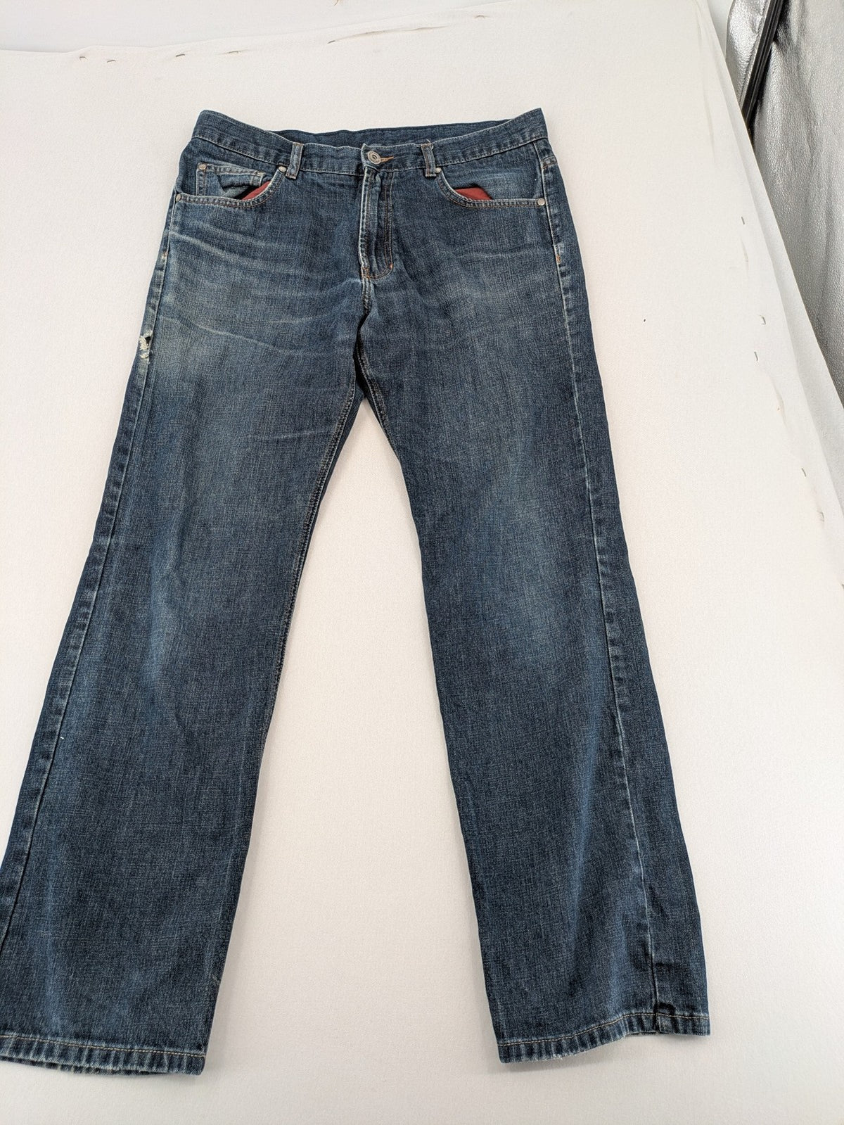 Indygo blue straight jeans 5-pocket style with subtle red pocket detail, cotton material.
