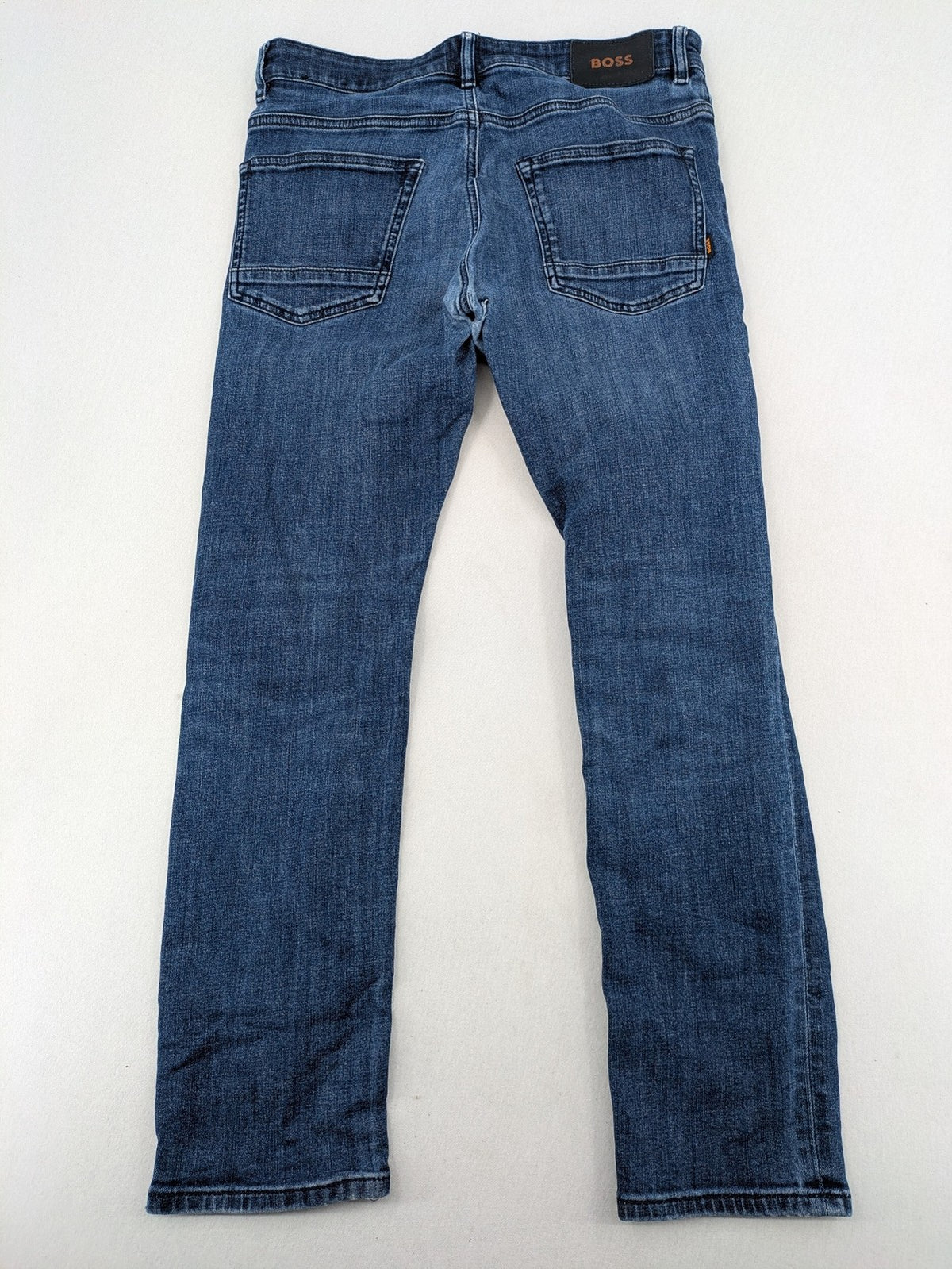BOSS blue slim fit jeans with logo, five-pocket design, and button fly.