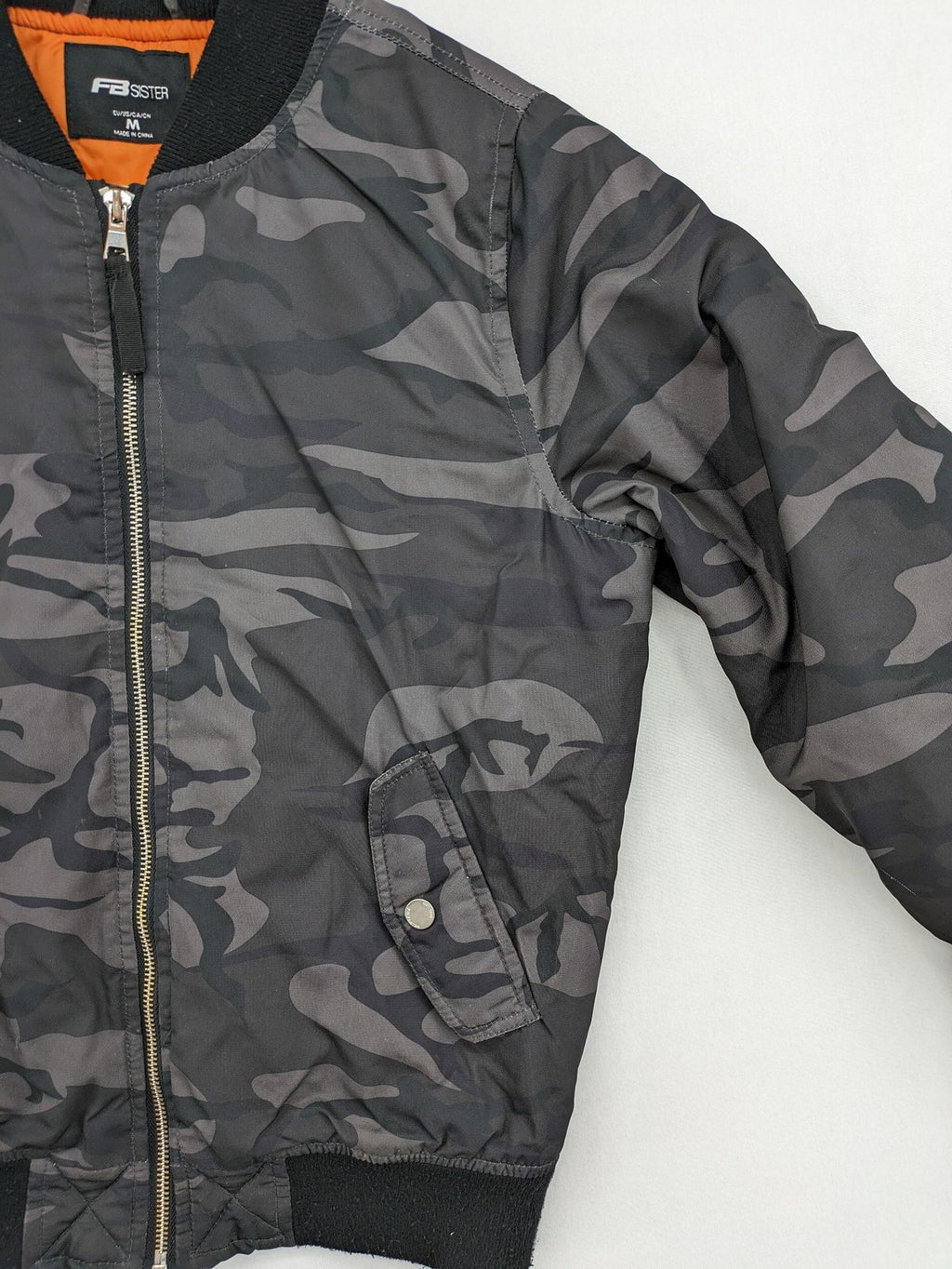 FB Sister orange bomber jacket with gray camouflage pattern and quilted lining.