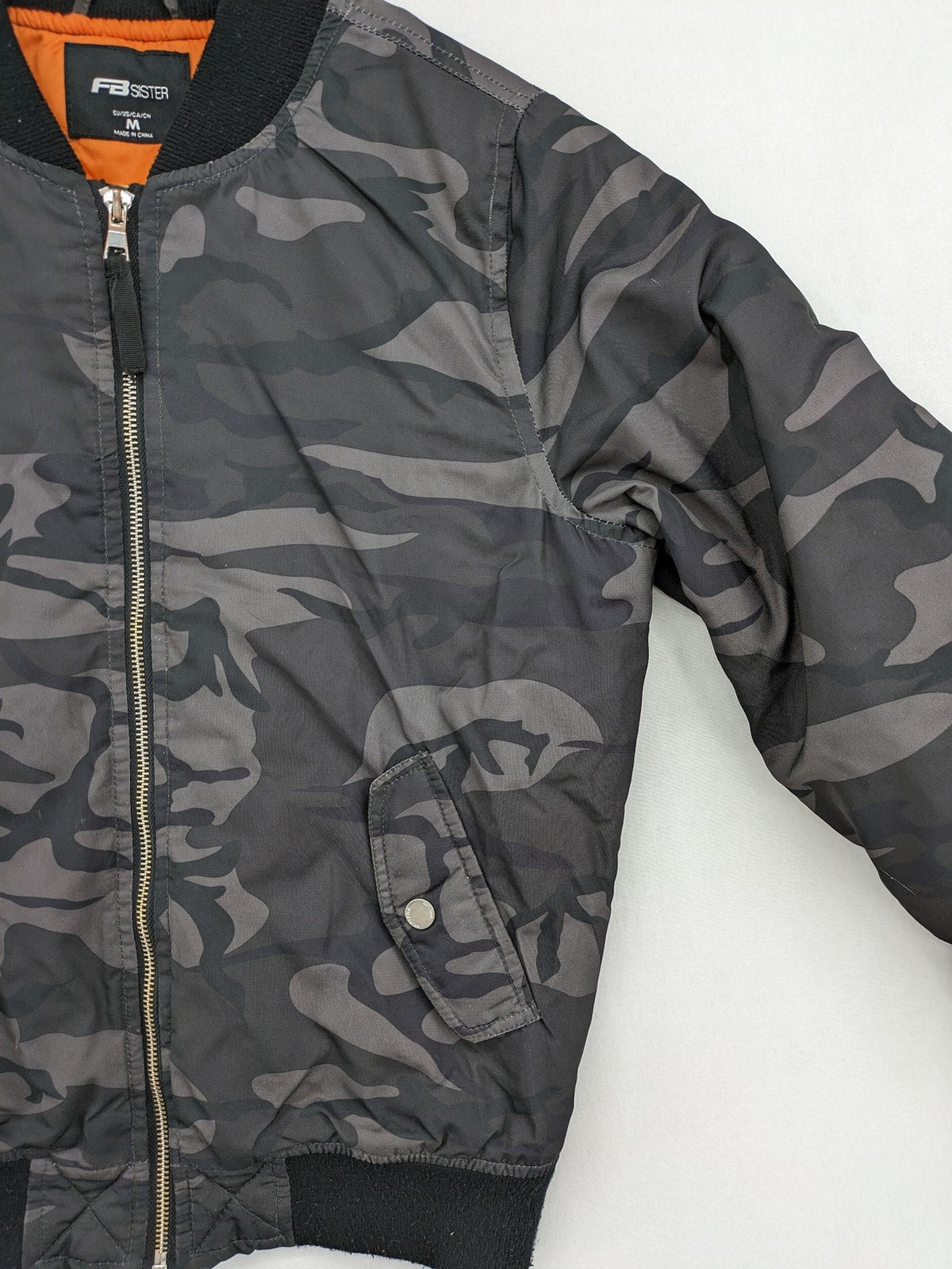 FB Sister orange bomber jacket with gray camouflage pattern and quilted lining.