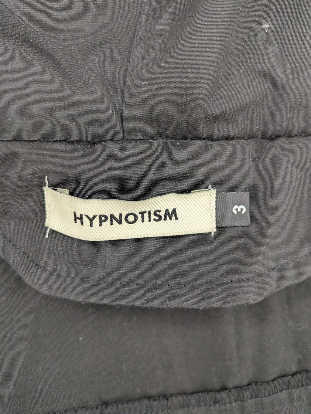 Hypnotism grey windbreaker jacket with hood, snap buttons, and zip closure.