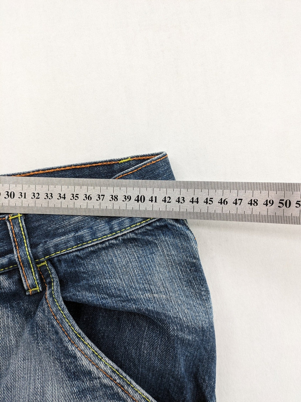 Identic orange straight jeans with paneled design and contrasting yellow stitching.